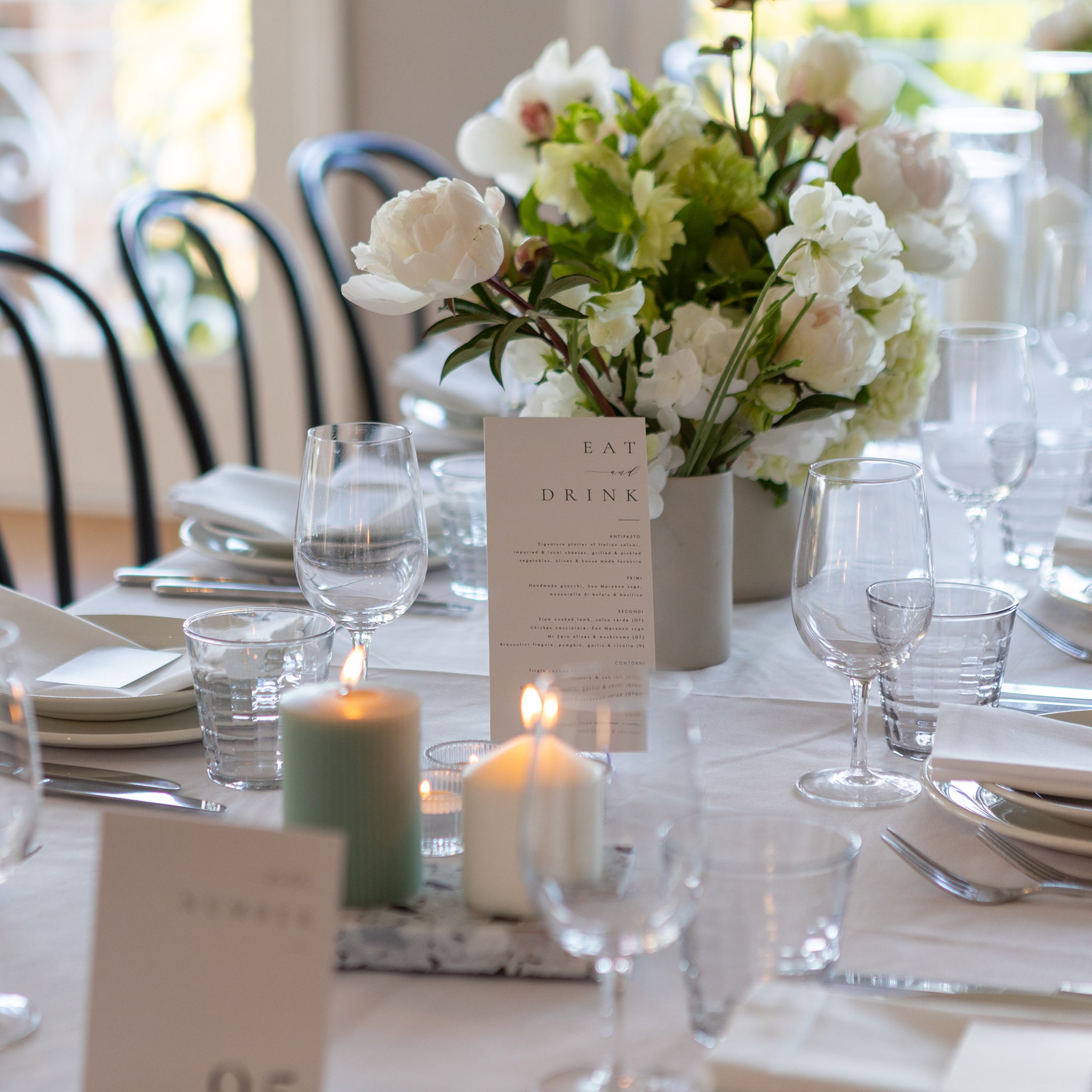 Wedding table styled with Insieme Homewares terrazzo tray holding pillar candles, surrounded by glassware, menus, and a white floral arrangement — perfect for refined, romantic celebration settings.