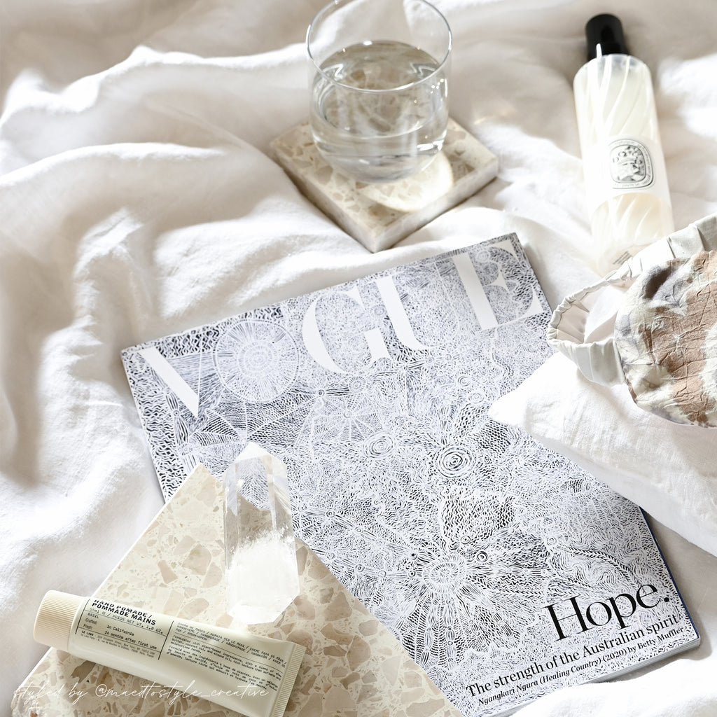 Insieme Homewares terrazzo coasters and platter in Estate styled on a bed with a glass of water, skincare, crystals, and Vogue magazine — a serene setup for slow mornings, self-care, and intentional living.