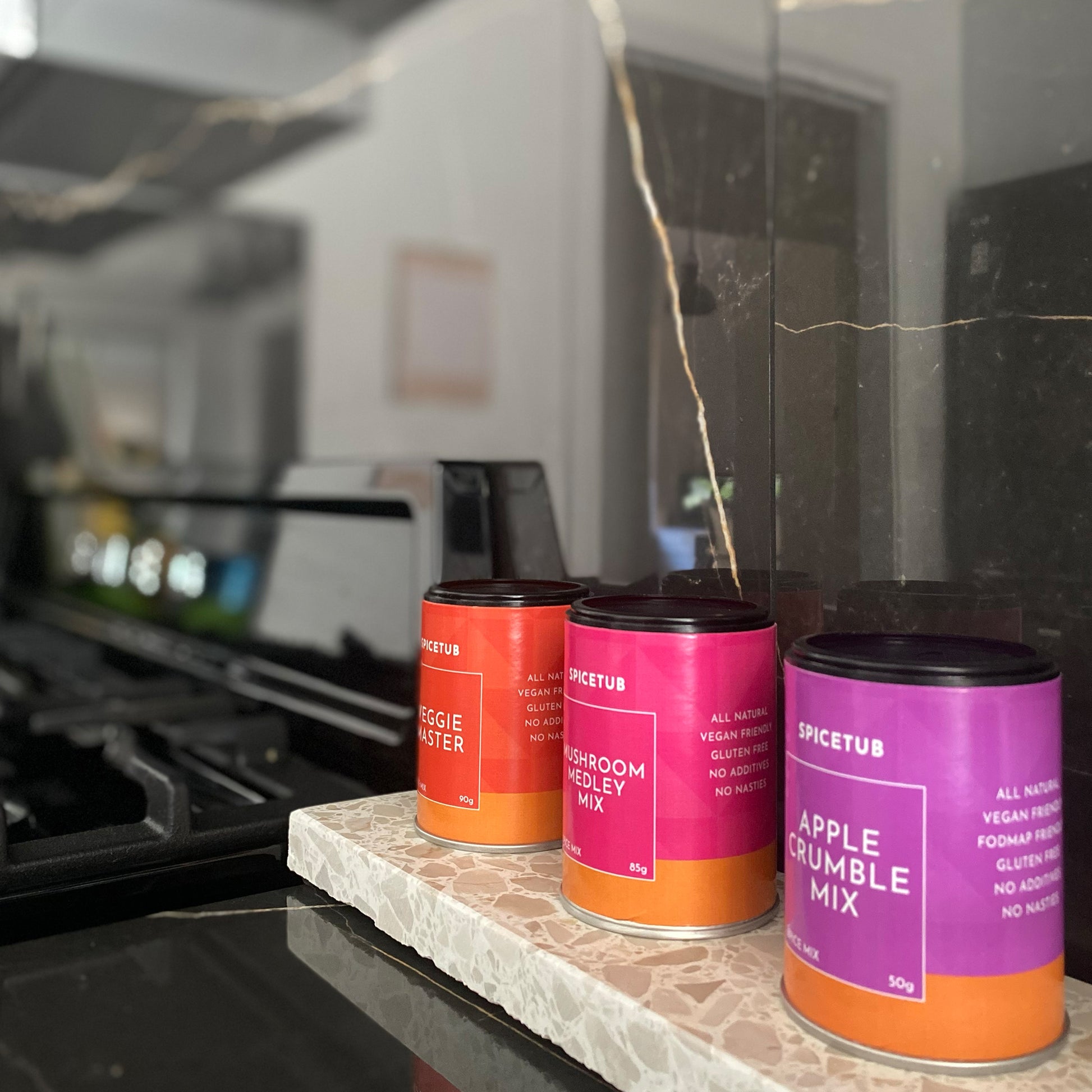 Spicetub spice mixes lined up on a terrazzo platter in a modern kitchen, capturing rich colour and sleek countertop styling.