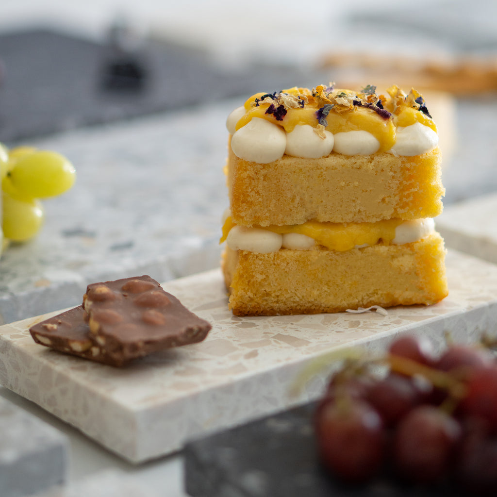 Estate platter styled with cake, chocolate and fruit; macro view of subtle organic edges and surface detail.
