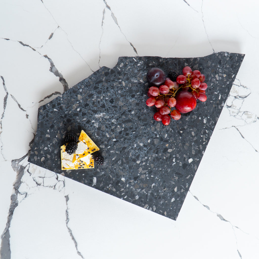 Flat lay of an Inverno organic terrazzo platter styled with chocolate bark and red fruit.