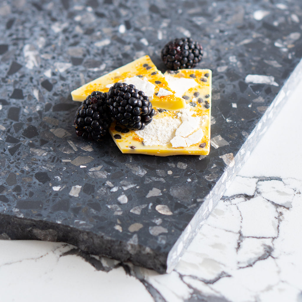 Close-up of artisan chocolate bark with blackberries on a Inverno terrazzo platter.