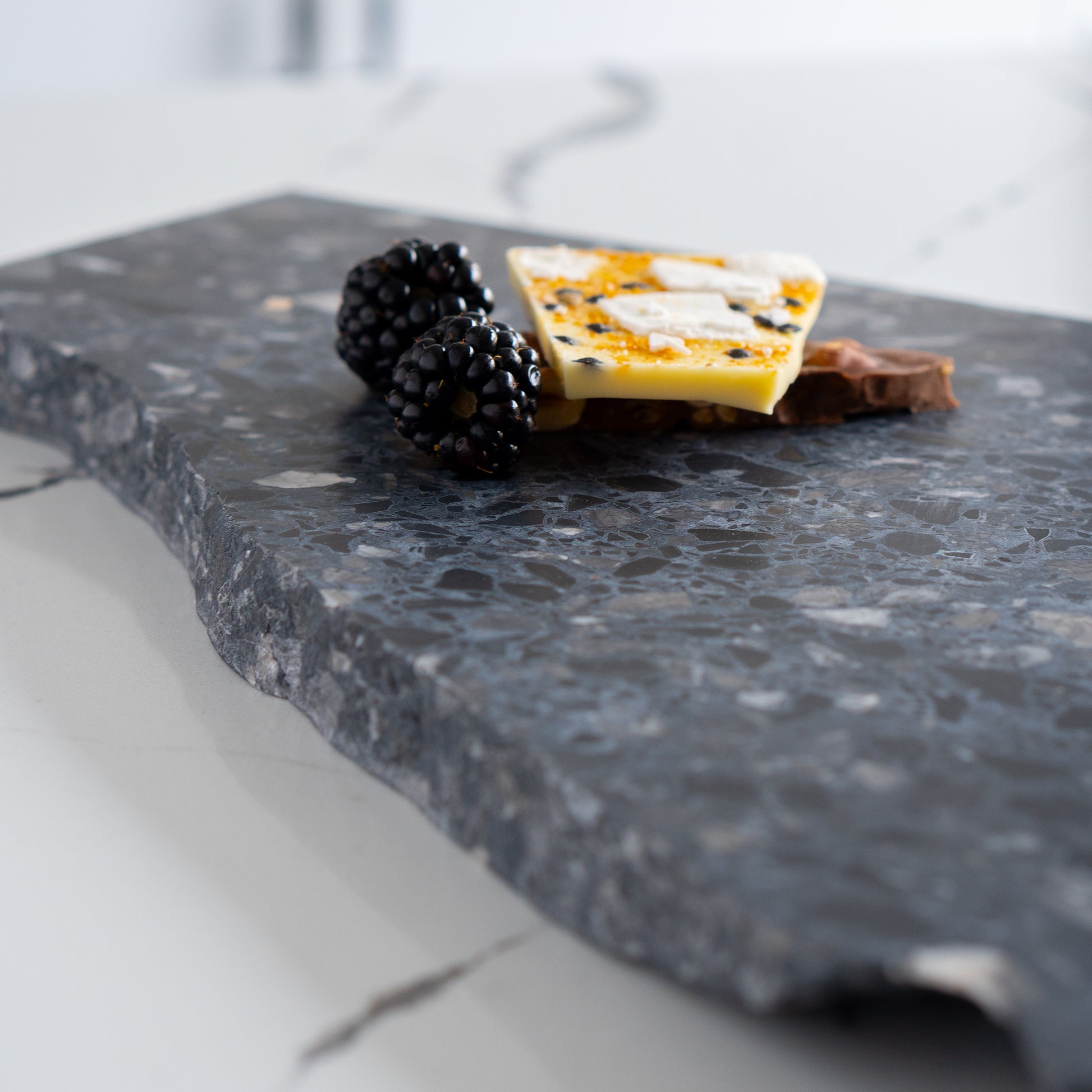 Chocolate bark and blackberries styled on the edge of an Inverno organic terrazzo platter.
