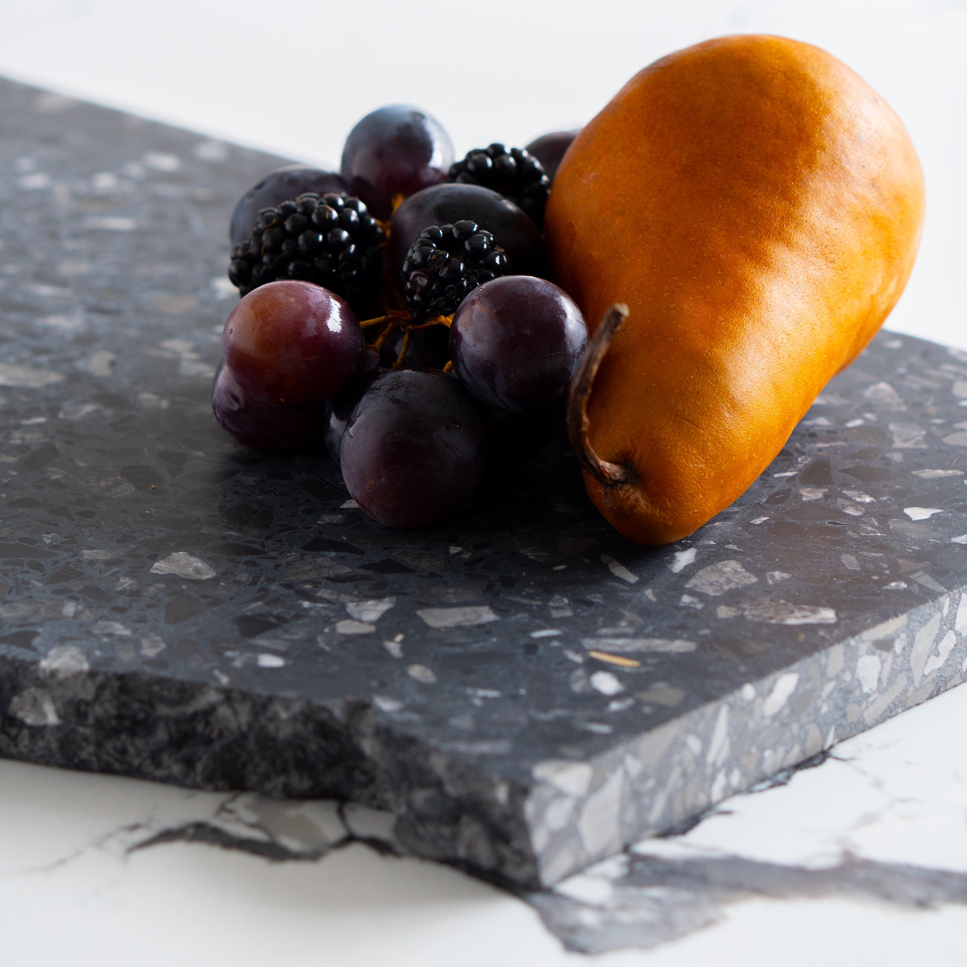 Inverno terrazzo platter with pear, grapes, and blackberries styled on white marble.