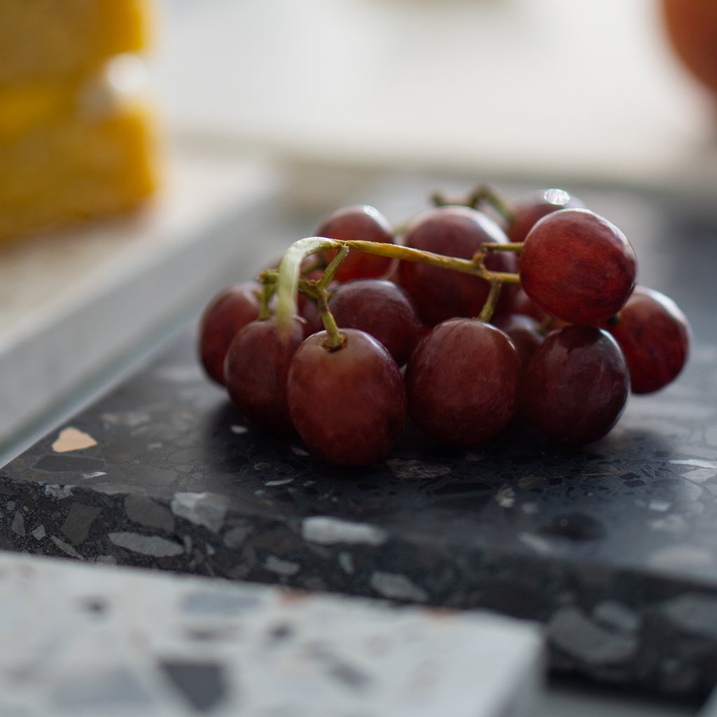 Grapes on top of an Inverno terrazzo platter; close view of cool dark terrazzo finish.